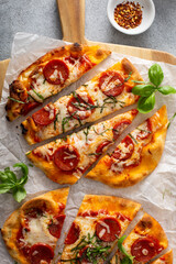 Wall Mural - Flatbread pepperoni pizza topped with fresh basil sliced, top view