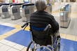 車椅子に乗って駅の改札を通る高齢男性