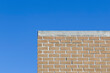 Top Edge of an Exterior Tan Brick Wall against a Clear Blue Sky
