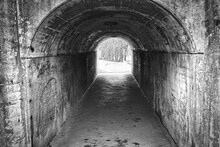 Grayscale Shot Of A Tunnel With Old Stony Walls