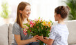 © JenkoAtaman - Girl giving flowers to woman on Mothers Day