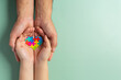 © artit - Adult and child hands holding jigsaw puzzle heart shape, World Autism Awareness Day