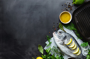 Poster - Fresh borabo fish with grill pan and ingredients for cooking on dark background top view copy space. Delicious and healthy food