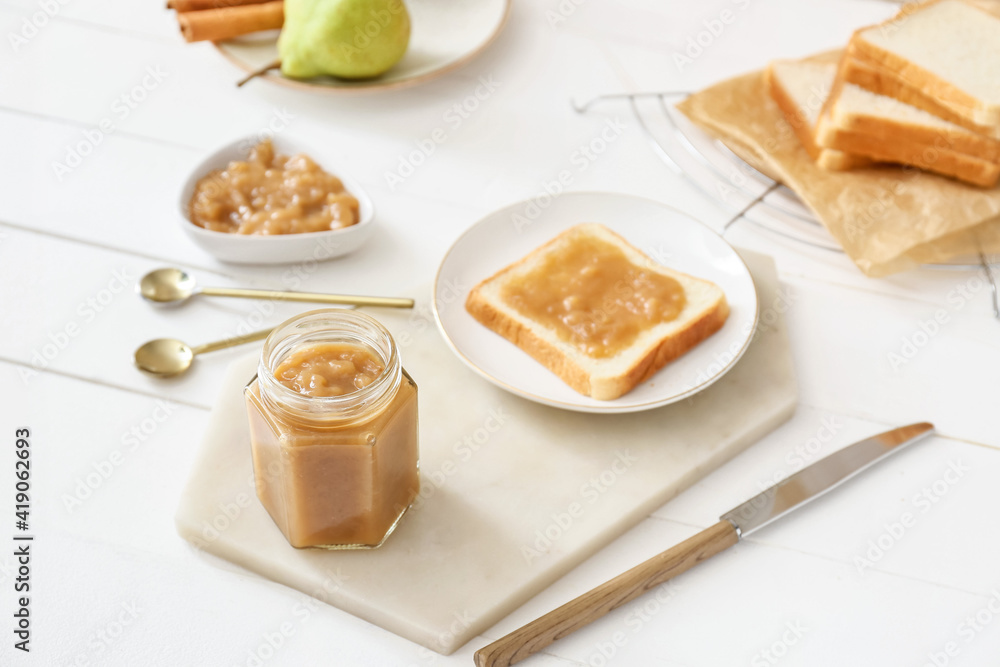 Jar of tasty pear jam with bread on table