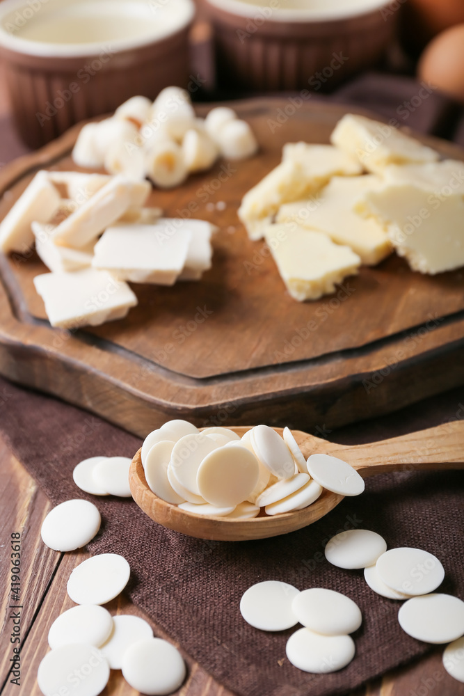 Spoon with chocolate drops on wooden background