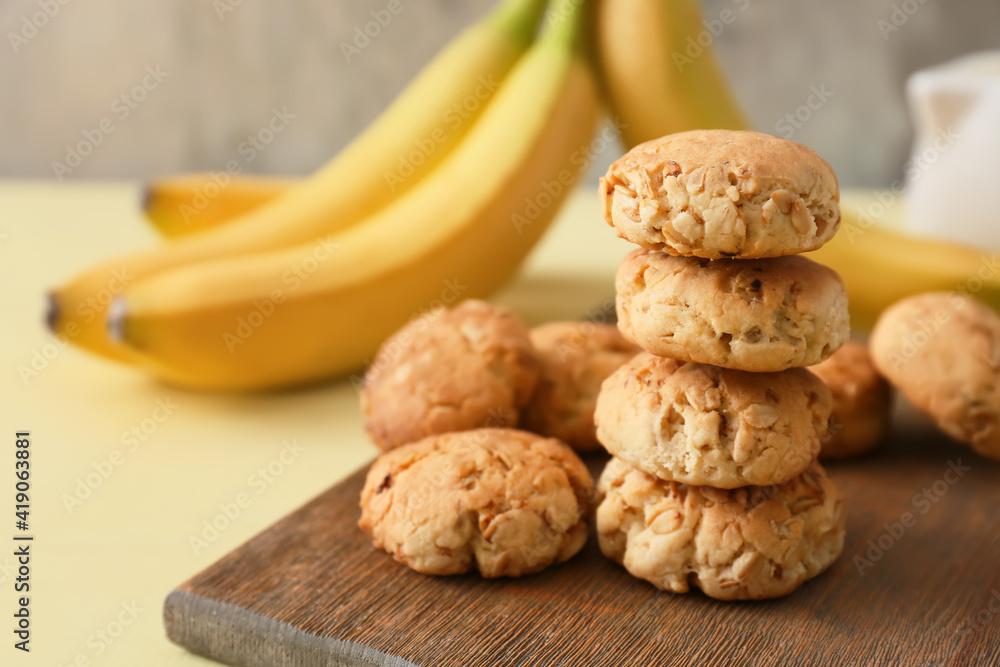 Board with tasty banana cookies on color background
