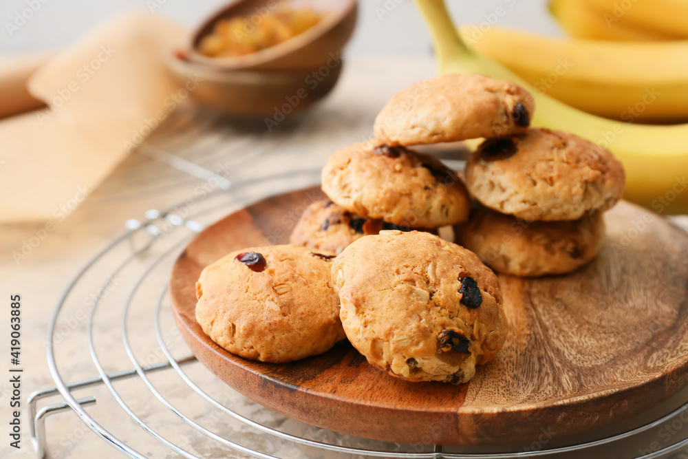 Plate with tasty banana cookies on light background