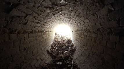 Wall Mural - exit of old abandoned oval brick drainage tunnel of the 19th century littered with garbage in the da
