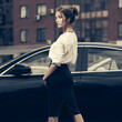 Young fashion business woman in white shirt and pencil skirt next to her car