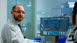 © DC Studio - Portrait of scientist man looking at camera sitting in modern equipped laboratory. Scientist doctor examining virus evolution using high tech typing on computer chemistry tools for scientific research