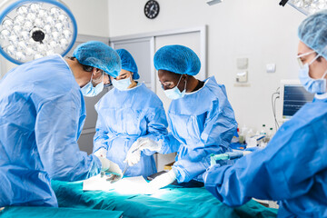 Wall Mural - Surgical team performing surgery in modern operation theater,Team of doctors concentrating on a patient during a surgery,Team of doctors working together during a surgery in operating room,