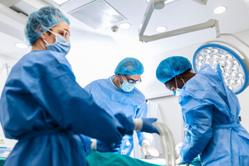 Wall Mural - Group of medical team urgently doing surgical operation and helping patient in theater at hospital. Medical team performing surgical operation in a bright modern operating room