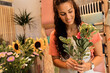 Young woman working in flower shop and making bouquet for customer.	