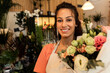 Portrait of young woman holding bouquet in flower shop.