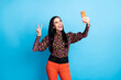 © deagreez - Photo of positive excited young woman make v-sign take selfie hold phone isolated on blue color background