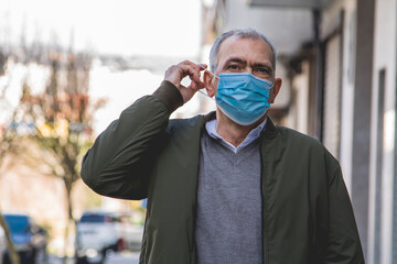 Wall Mural - casual adult man with medical mask protecting from coronavirus around the city