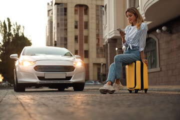 Canvas Print - Woman ordering taxi with smartphone on city street