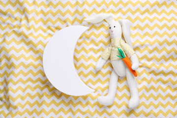 Canvas Print - Crescent shaped child's night lamp and toy rabbit on yellow fabric, flat lay