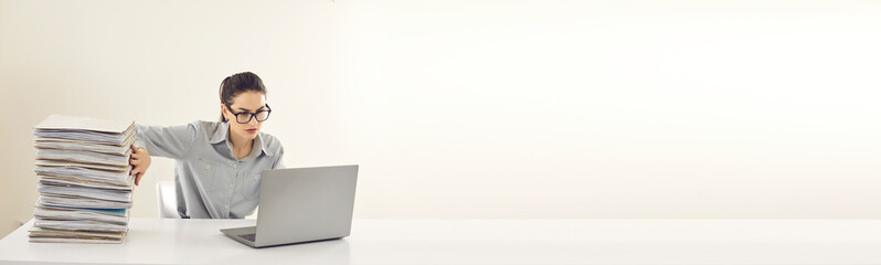 No more piles of papers, store them in digital computer database instead. Office manager or accountant sitting at desk, doing paperwork, entering data in electronic system on laptop. Copy space banner