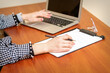 © okskukuruza - Female hands holding pen under the document and working with laptop at the table in an office
