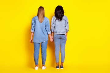 Sticker - Full length rear photo of two ladies standing hold each other arms isolated on yellow color background