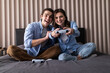 © F8  \ Suport Ukraine - Young cheerful couple play to video game on a couch