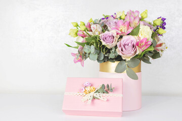 Beautiful bouquet of flowers in round box and pink gift box on a white table. Gift for holiday, birthday, Wedding, Mother's Day, Valentine's day, Women's Day. Floral arrangement in a hat box.