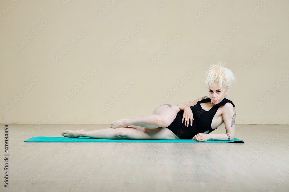 Beautiful fit slim woman resting on mat after doing her daily workout - obrazy, fototapety, plakaty 