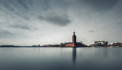 Wall Mural - Long exposure of a minimalist view of the capital of Sweden-Stockholm. In the middle of the picture is an iconic building-City Hall, which is reflected in the lake. The clouds are moving in the sky.