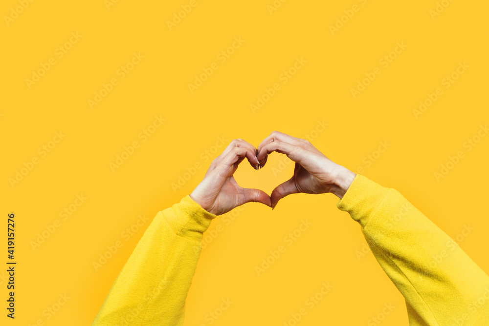 Hands making heart shape isolated on a yellow background - Love and minimal fashion concept - obrazy, fototapety, plakaty 