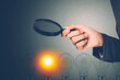 Businessman holding magnifying glass for search idea with light bulb with bright is metaphor, innovation and inspiration, solution and imagination, decision and choice for success, business concept.