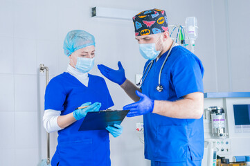 The male surgeon explains to the female anesthesiologist. And she makes notes on the tablet. Medicine concept. Operating room.