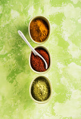 Wall Mural - Powder spices spicy turmeric, coriander and hot chili  in bowls on a concrete background, top view