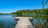 Fototapeta Pomosty - Long Old wooden pier and beautiful lake. Empty on small country lake. of summer. Place for text and fishing