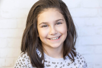 Portrait of a happy smiling latin child girl on white brick wall background