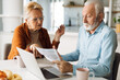© Goran - Frustrated senior couple sitting at home and checking their home finances