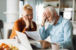 © Goran - Worried senior couple feeling stressed while have to pay their bills over Internet