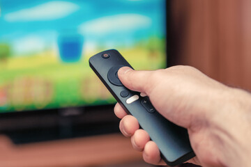 A man with a remote control in his hand is watching TV