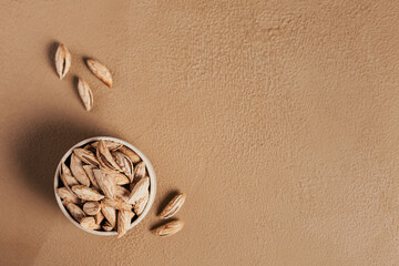 Wall Mural - Pile of Almond nuts in a bowl on a white background. Fresh nuts in their shells.