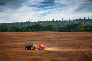 Wall Mural - Farmer with tractor seeding crops at field