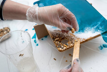 Artist's Hands Decorating A Wooden Serving Board With Seashells And Stones, Epoxy Resin, Selective Focus, Imitation Of The Sea