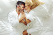 © Dusan Petkovic - Top view of a middle-aged couple in love in bathrobes on honeymoon lying in a bed and cuddling.