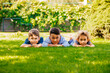 © oksix - Portrait of three little children lying on a green grass