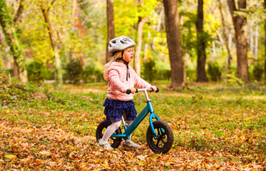 Wall Mural - Lovely girl riding balance bike in atumn park