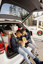 Twin Brothers Looking At Christmas Gifts In Trunk Of Car