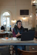 © Paul Bradbury/Caia Image - Businesswoman with headphones video conferencing at laptop in cafe