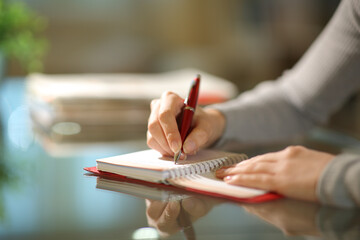 Woman hands writing on agenda in the night at home