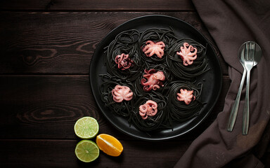 Black pasta, with baby octopus, dish, on a black wooden background, top view, no people,