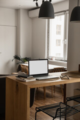 Wall Mural - Laptop computer with blank screen, notebooks on wooden table in warm sunlight room. Aesthetic minimal interior design template with mockup copy space. Blog, web, social media concept.