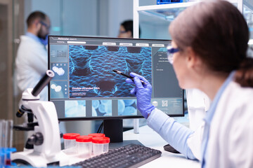 Wall Mural - professional biochemist analysing a medical experiment while working with her team to discover a vac